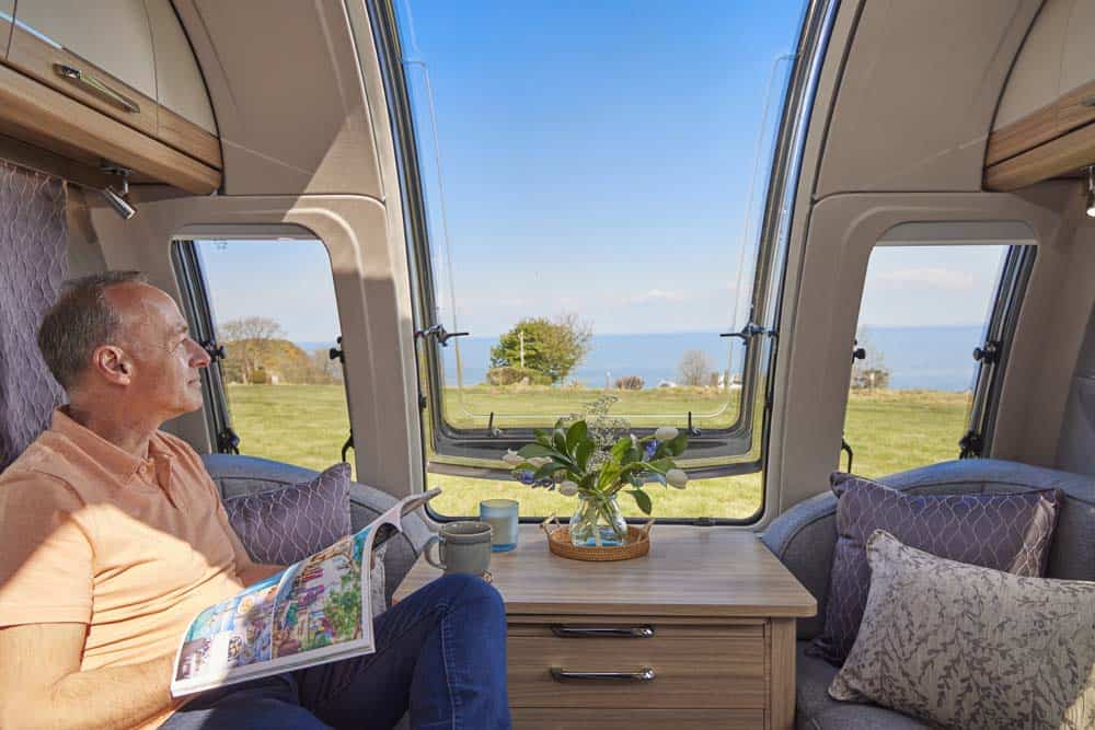 inside the Unicorn Series 5 with a man enjoying the stunning ocean view from the Bailey infinity window
